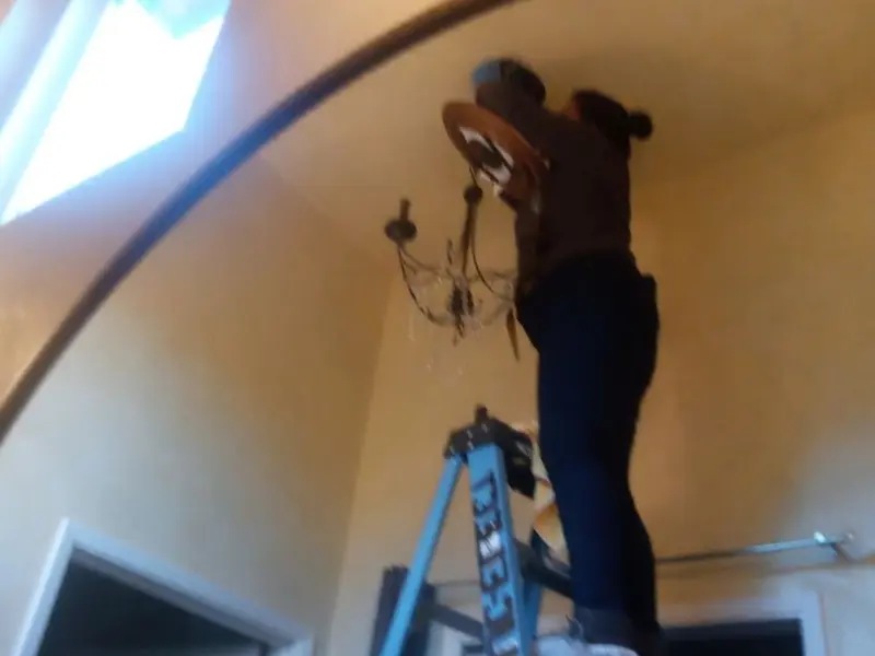 Electrician installing a chandelier in a Berkeley residence